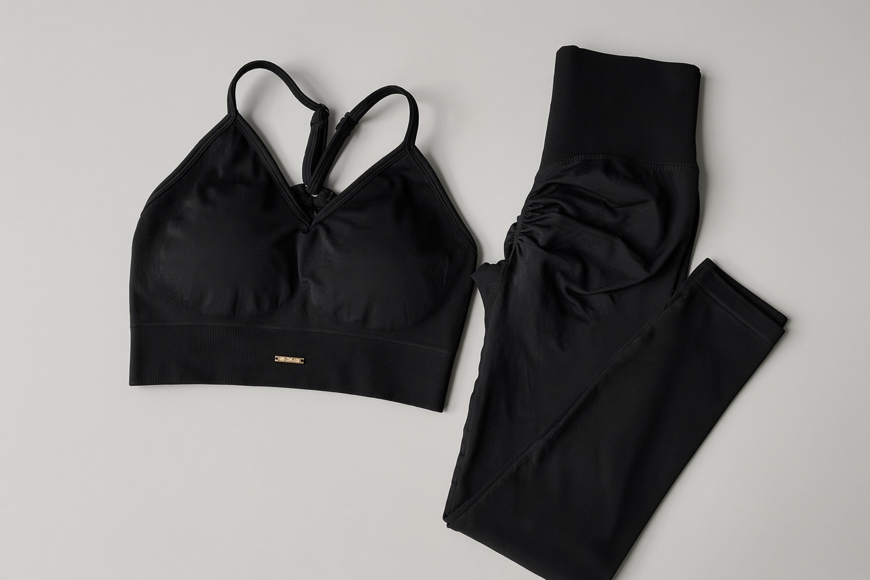 VELA Impact Set in Onyx laid flat — black matching sports bra and high-waist leggings